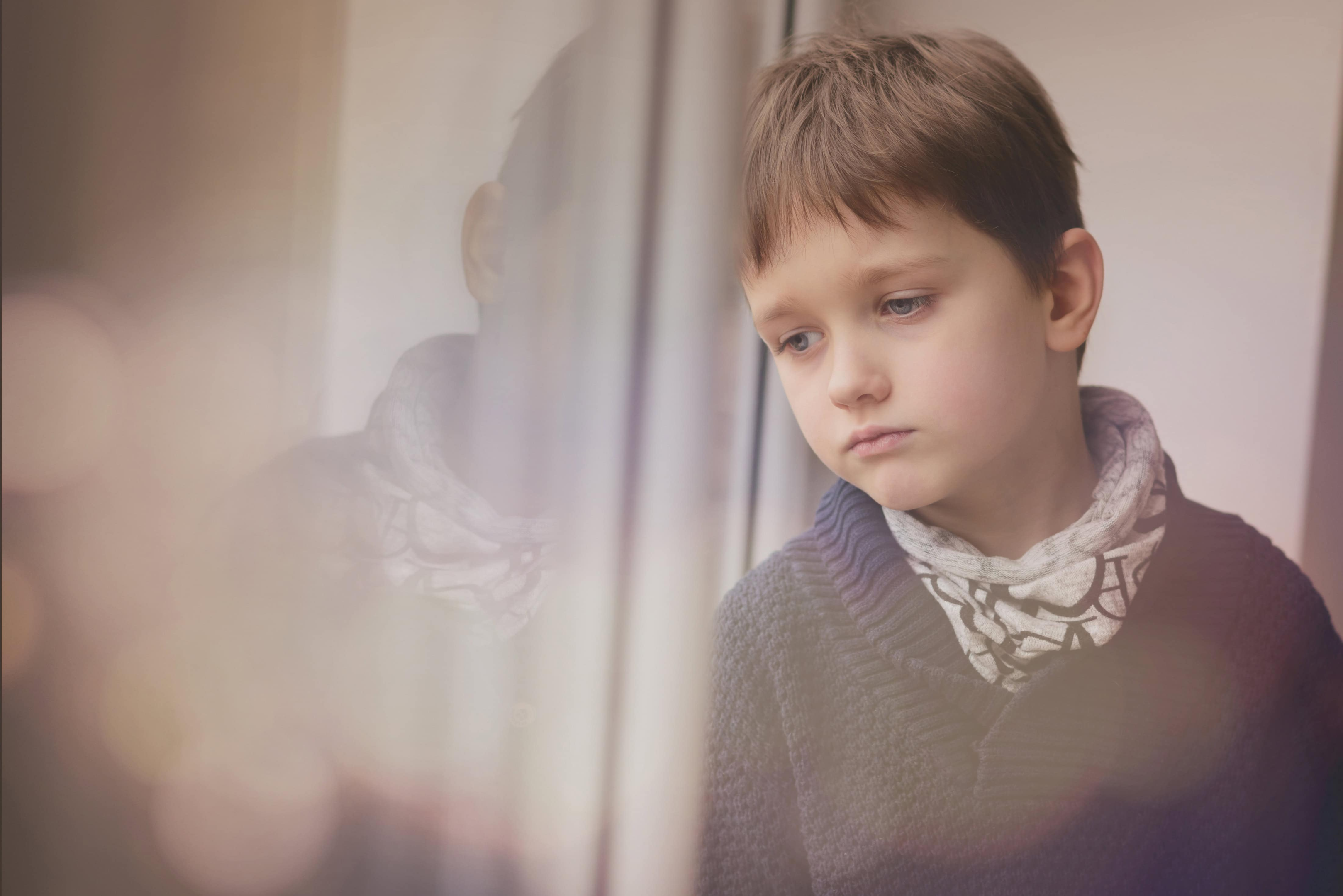A boy that was traumatized and is staring outside his window seeking hope and support.