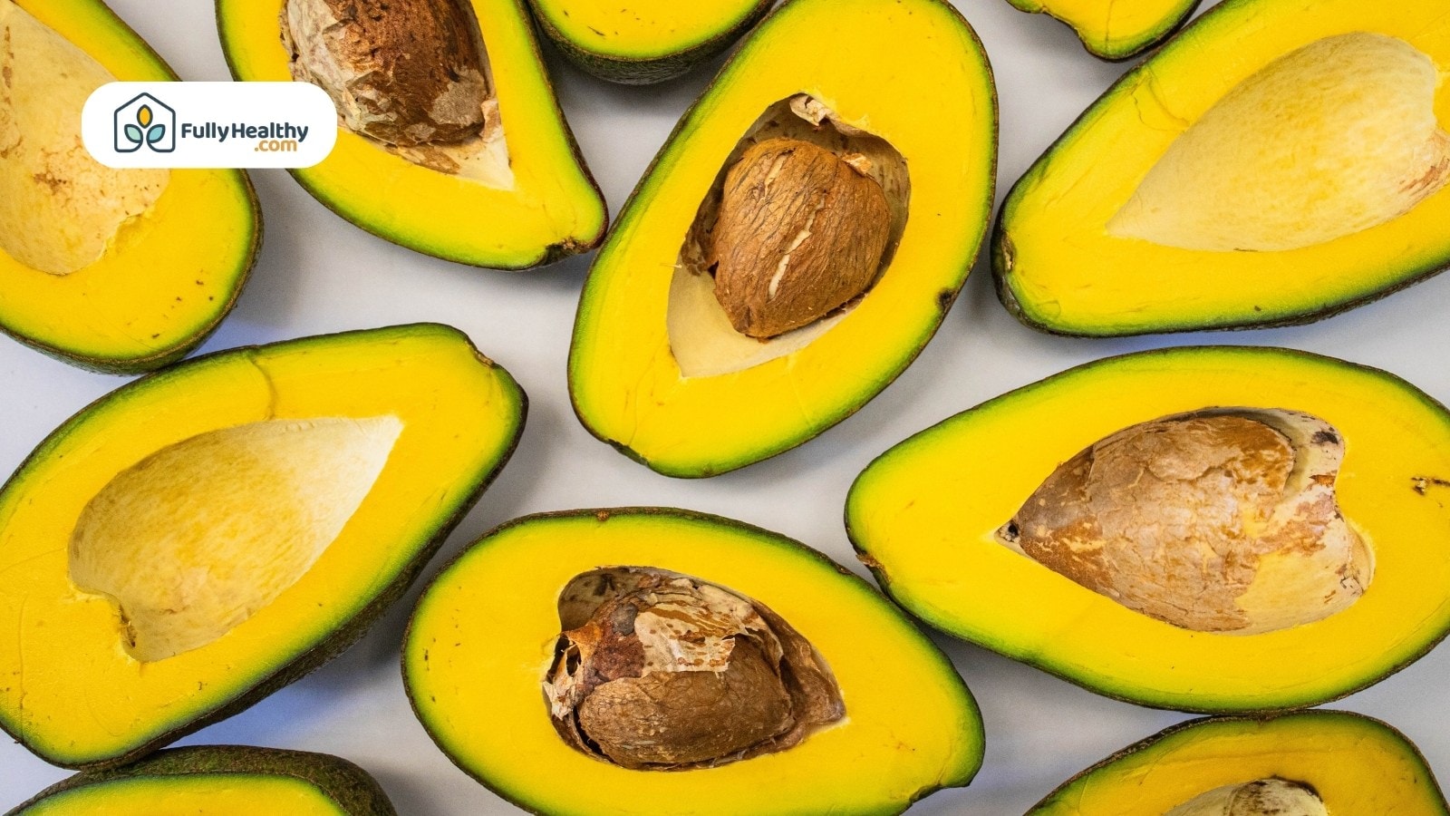 Multiple halved avocados showing large seeds and yellow flesh inside