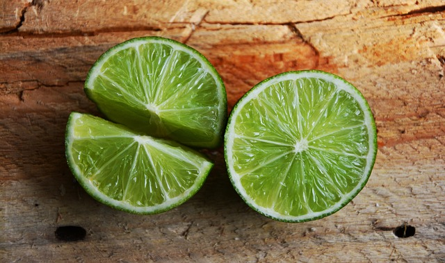 An image of two slices of lime fruit on a wooden table. 