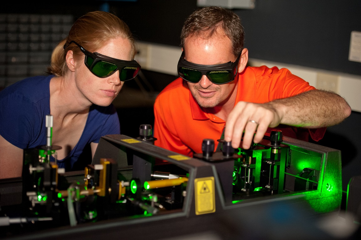 Laser specialists with safety goggles and equipment working on a Laser machine