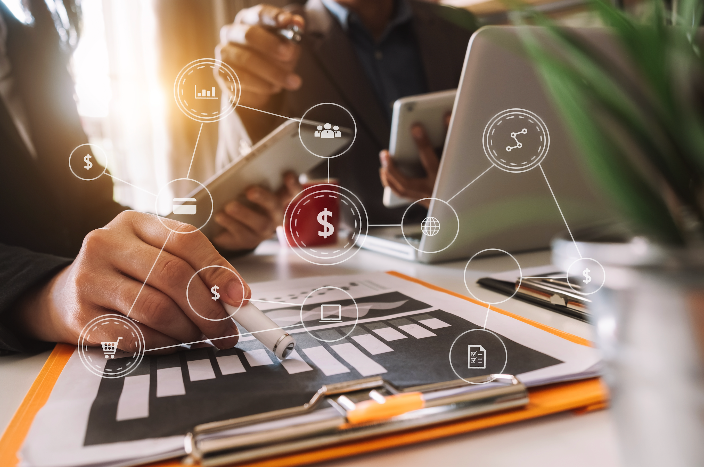 two marketing professionals reference a clip board on the desk with marketing icons floating above