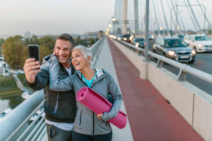 Happy couple holding a yoga mat snapping a selfie.