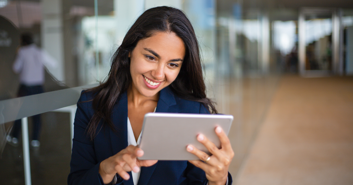 A smiling woman using a tablet in a modern office; exploring tax write-offs LLC expenses.