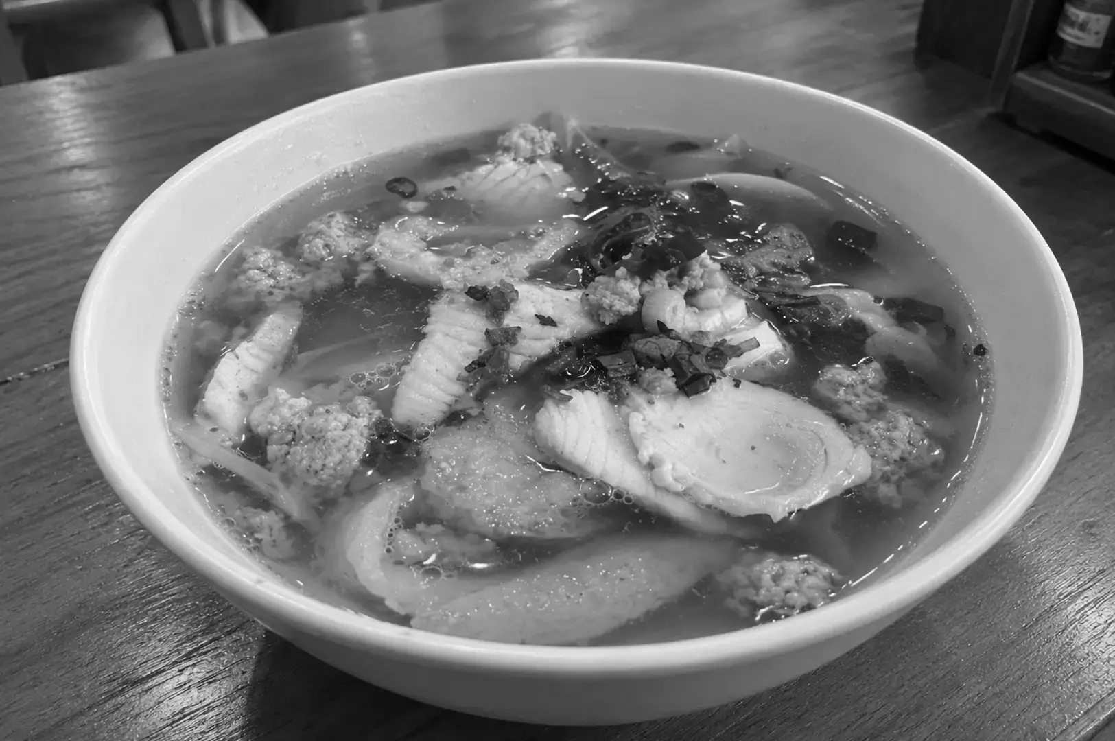 A bowl of Batang Fish Soup featuring thick slices of fish in a clear, light broth with fresh ingredients and herbs.