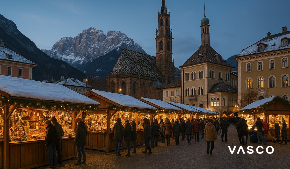 Mercatino di Natale italiano con le montagne alpine al crepuscolo.