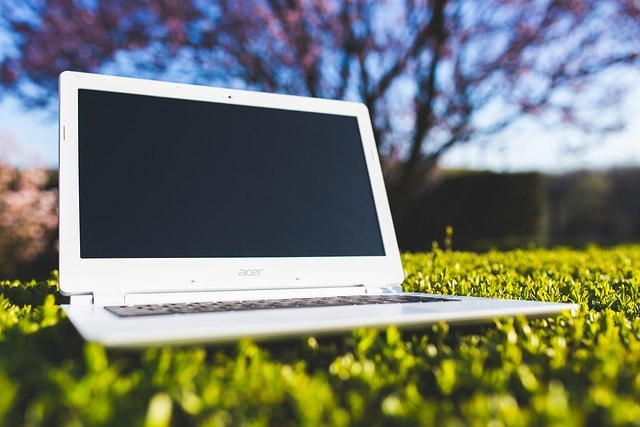 A laptop outside on the grass showing the flexibility of online writing courses.