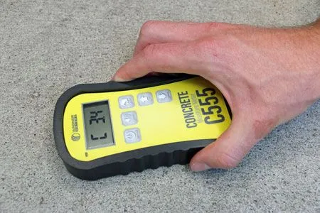 A person conducting a concrete moisture test with a concrete moisture meter