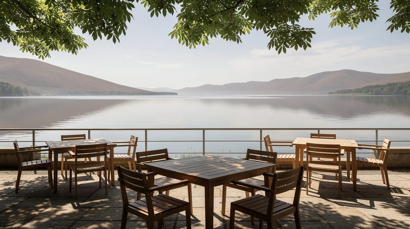 Una terrazza ombreggiata sul lago, con tavoli di legno affacciati sull'acqua e sulle colline.
