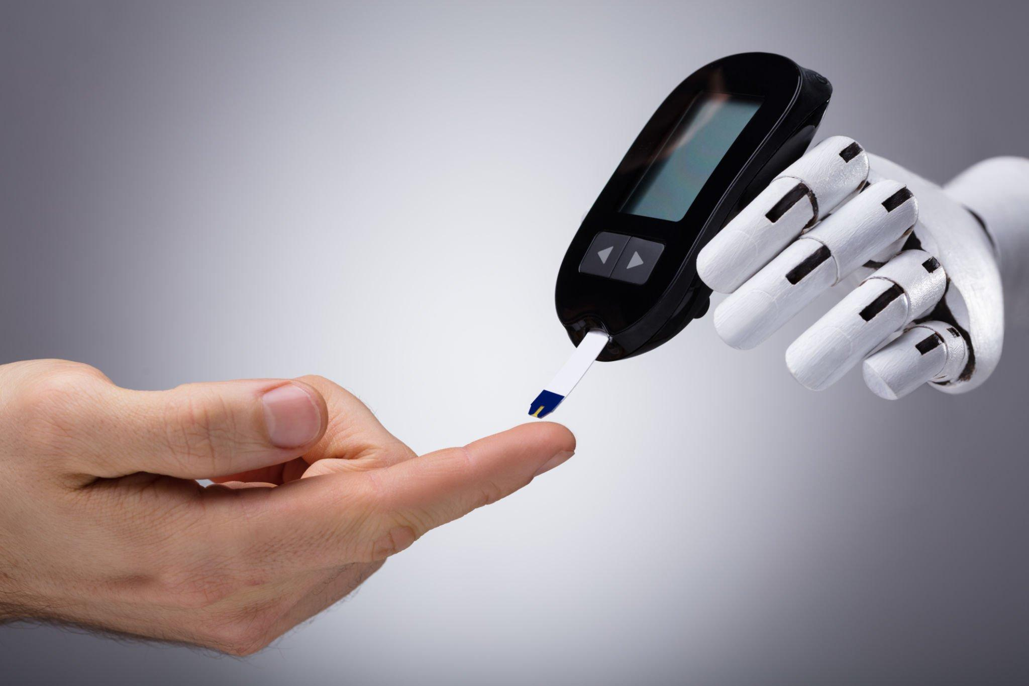 A hand and a robotic hand holding a glucose meter together.