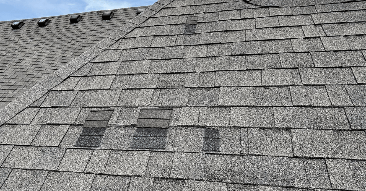 Asphalt roof with multiple patch repairs using mismatched shingles, showing signs of wear and poor past maintenance.