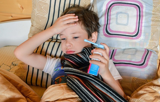 An image of a male child with strep throat in bed holding a can of throat spray.
