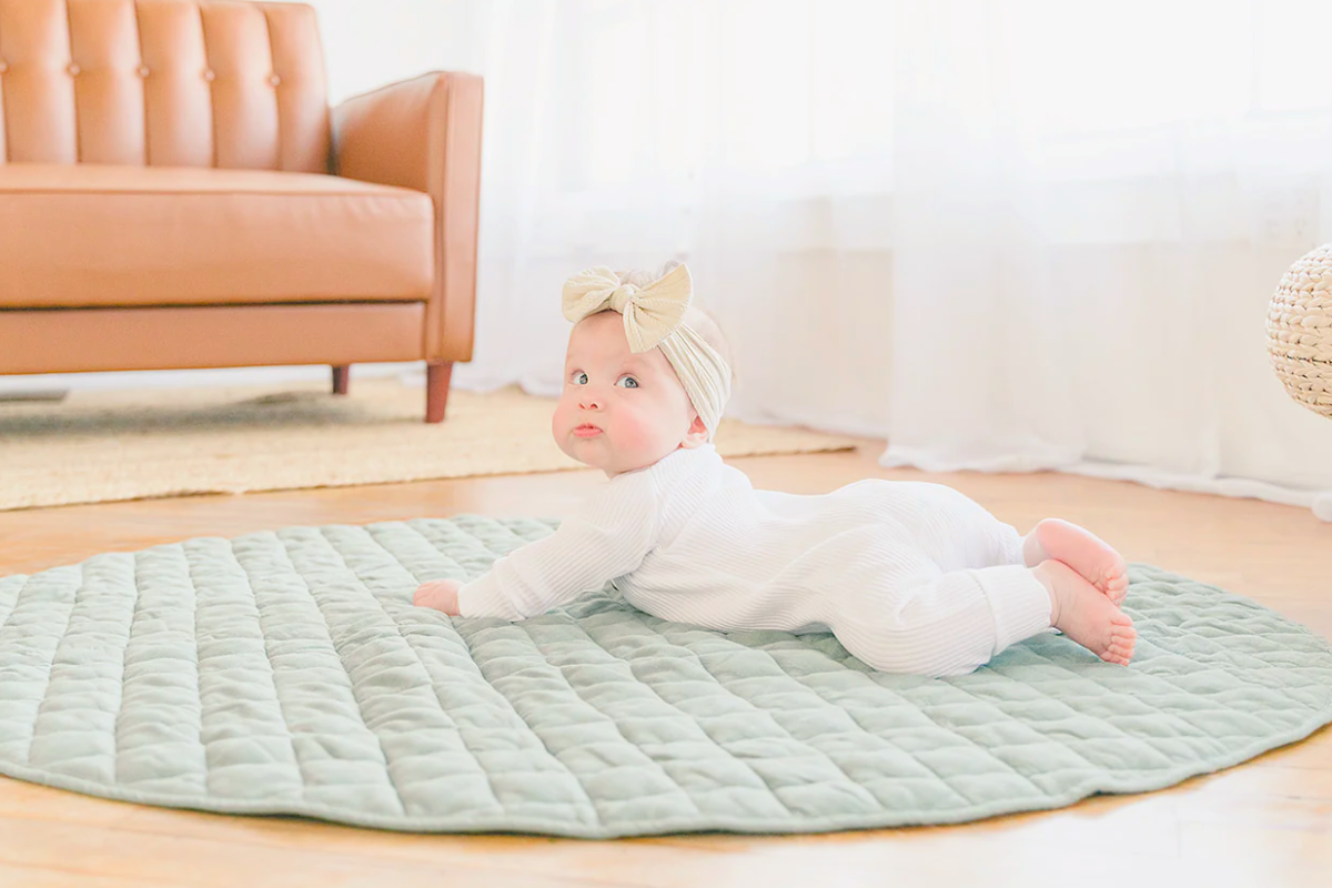 Baby doing tummy time on green playmat by Poppyseed Play