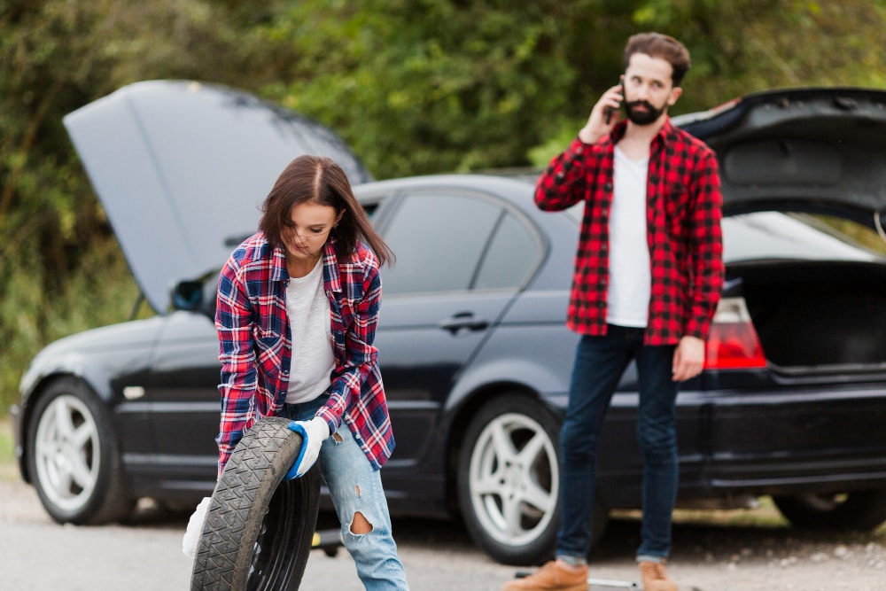 W razie problemów z samochodem w trasie, reaguj natychmiastowo. Źródło: https://www.freepik.com/free-photo/woman-holding-spare-tire-man-talking-phone_5381415.htm#fromView=search&page=1&position=40&uuid=eaf3e3b0-ea83-4f18-bba7-eb12efe37417&query=awaria+samochodu