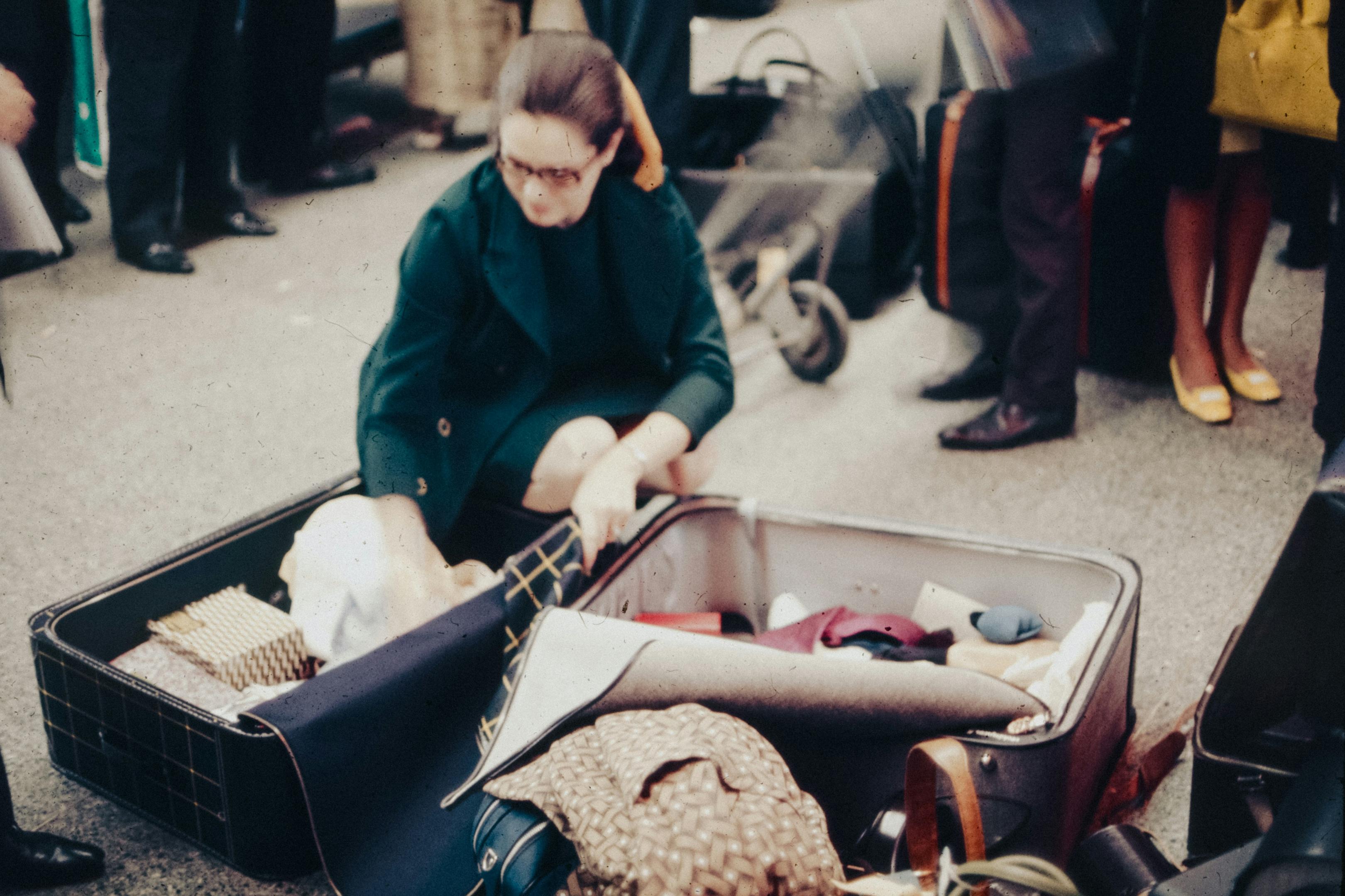 woman packing her open luggage at a busy airport terminal