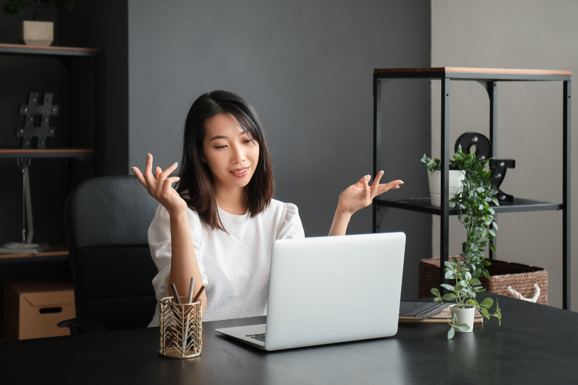Woman gesturing in confusion while speaking to someone on a video call in a home office