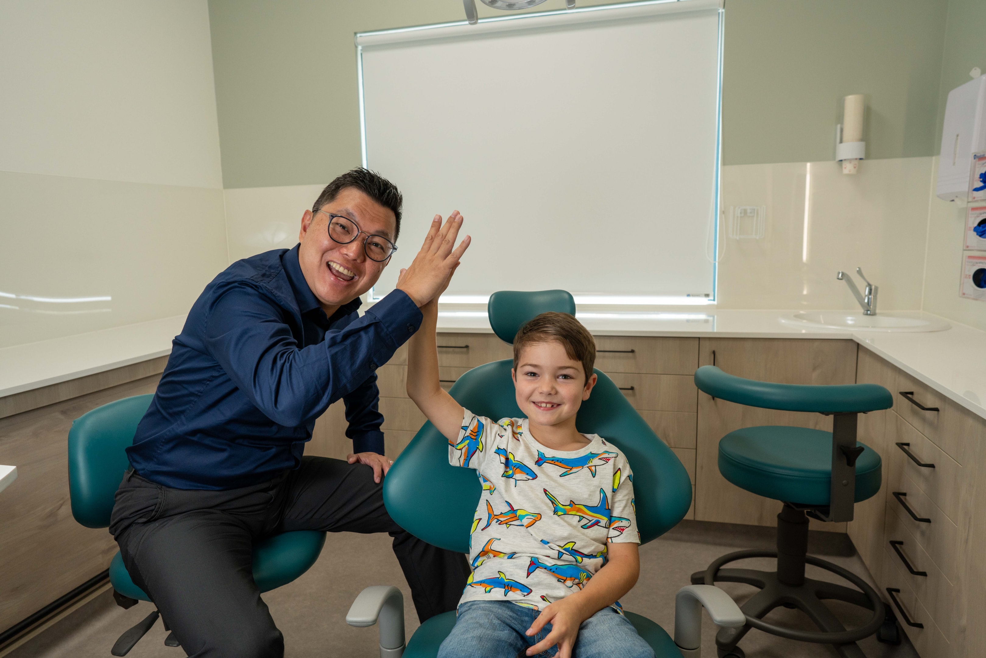 Orthodontist and young boy patient happy high five