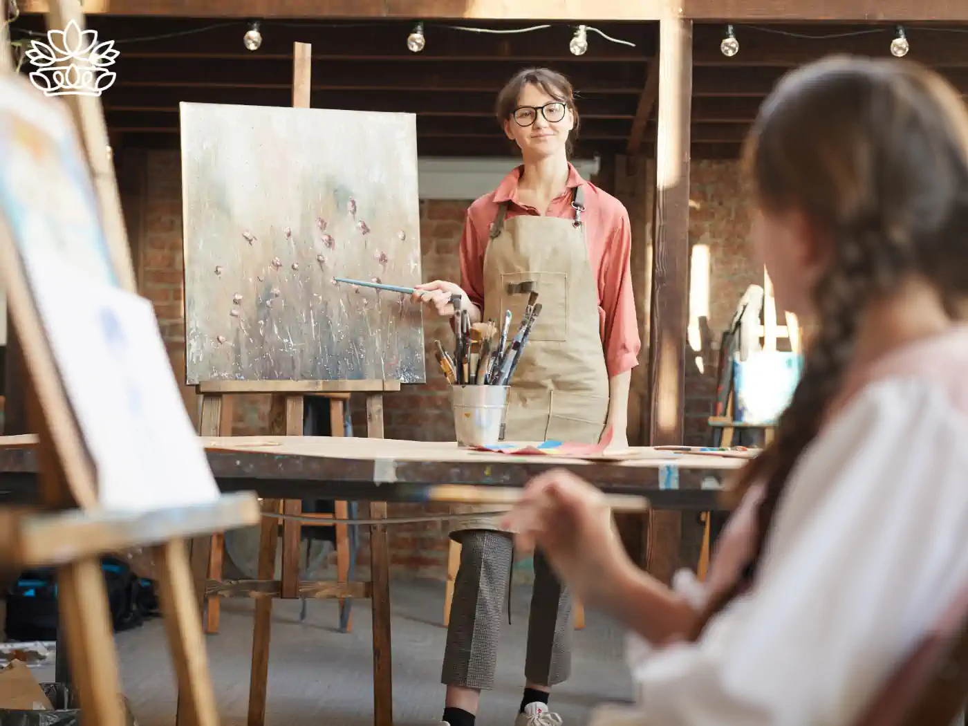 Inspirational art teacher guiding a student in a creative studio setting, nurturing artistic expression and talent, delivered with heart by Fabulous Flowers and Gifts.