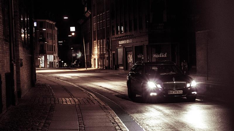 Car with bright headlights in dark street
