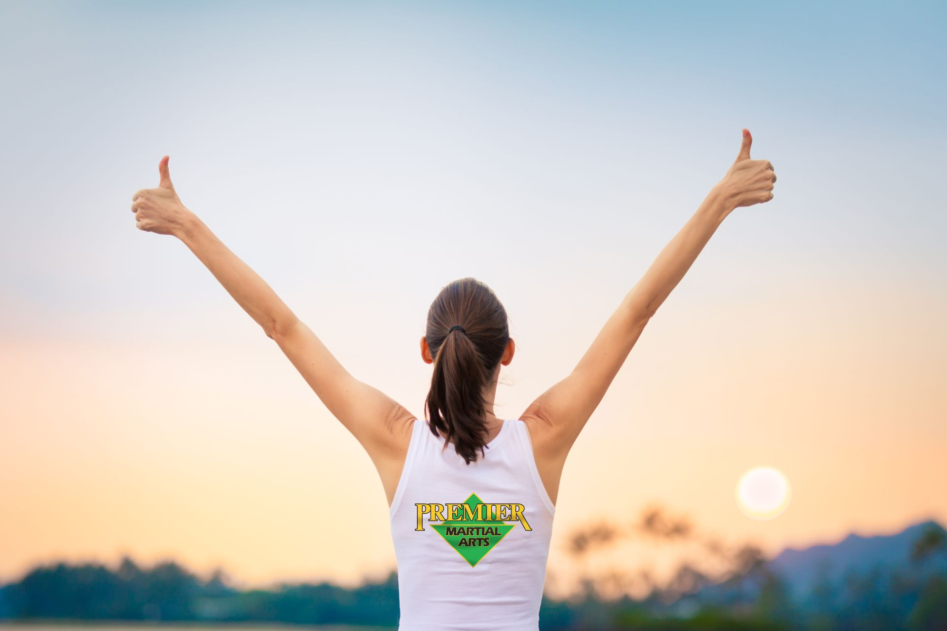 woman gives two thumbs up while wearing premier martial arts shirt