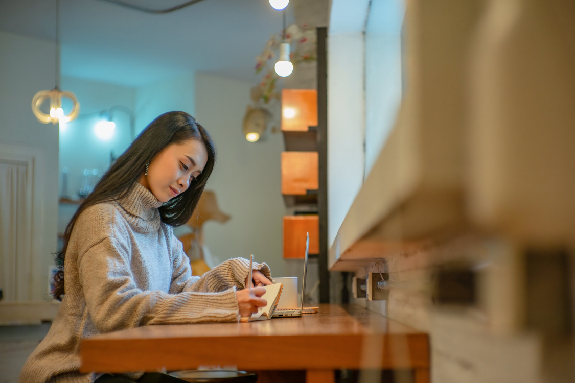 Filipino remote worker writing role notes in a cozy workspace to understand task expectations.