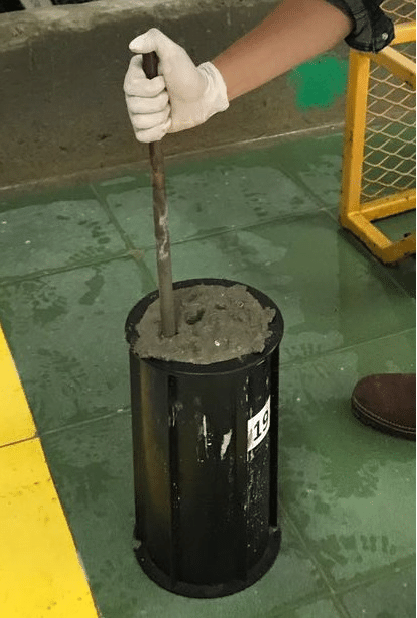Illustration of a tamping rod being used in concrete testing