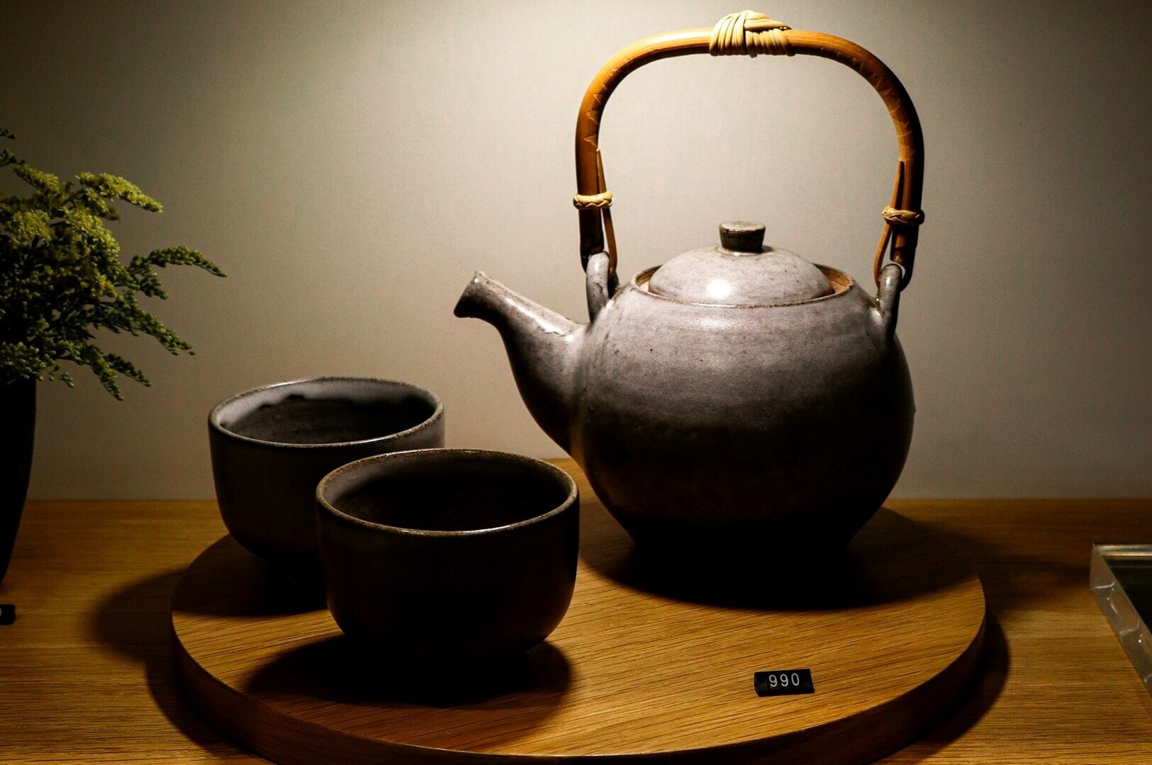 A wooden stand displays a teapot and two cups, set in the serene ambiance of the Chinese Tea Room, Singapore.