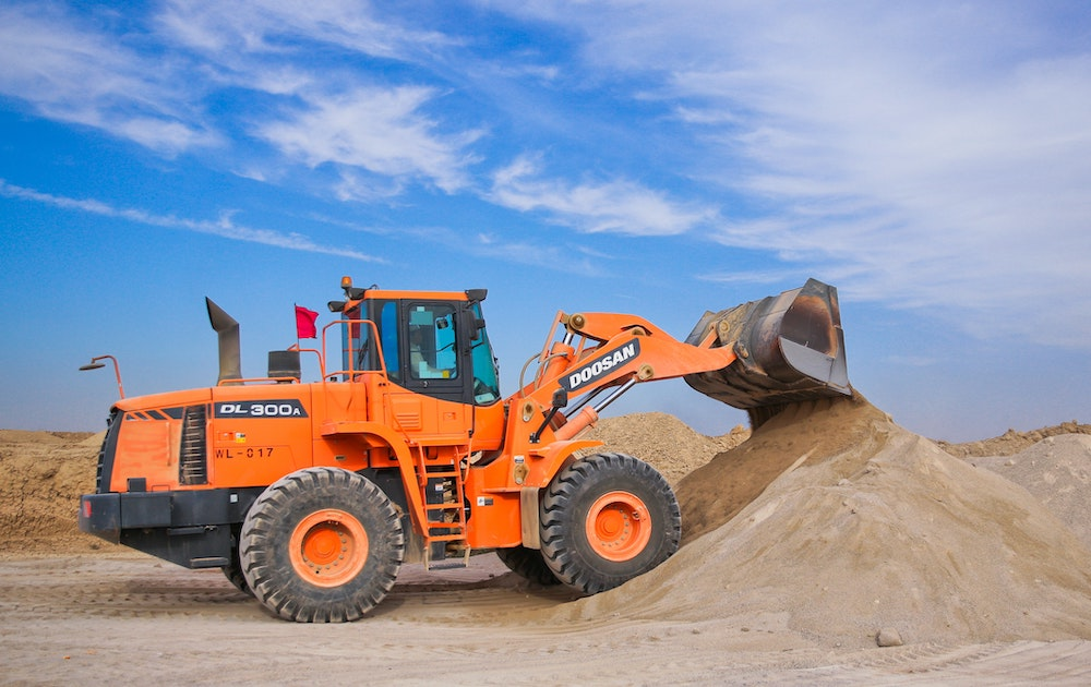 Construction equipment piling sand for construction project.