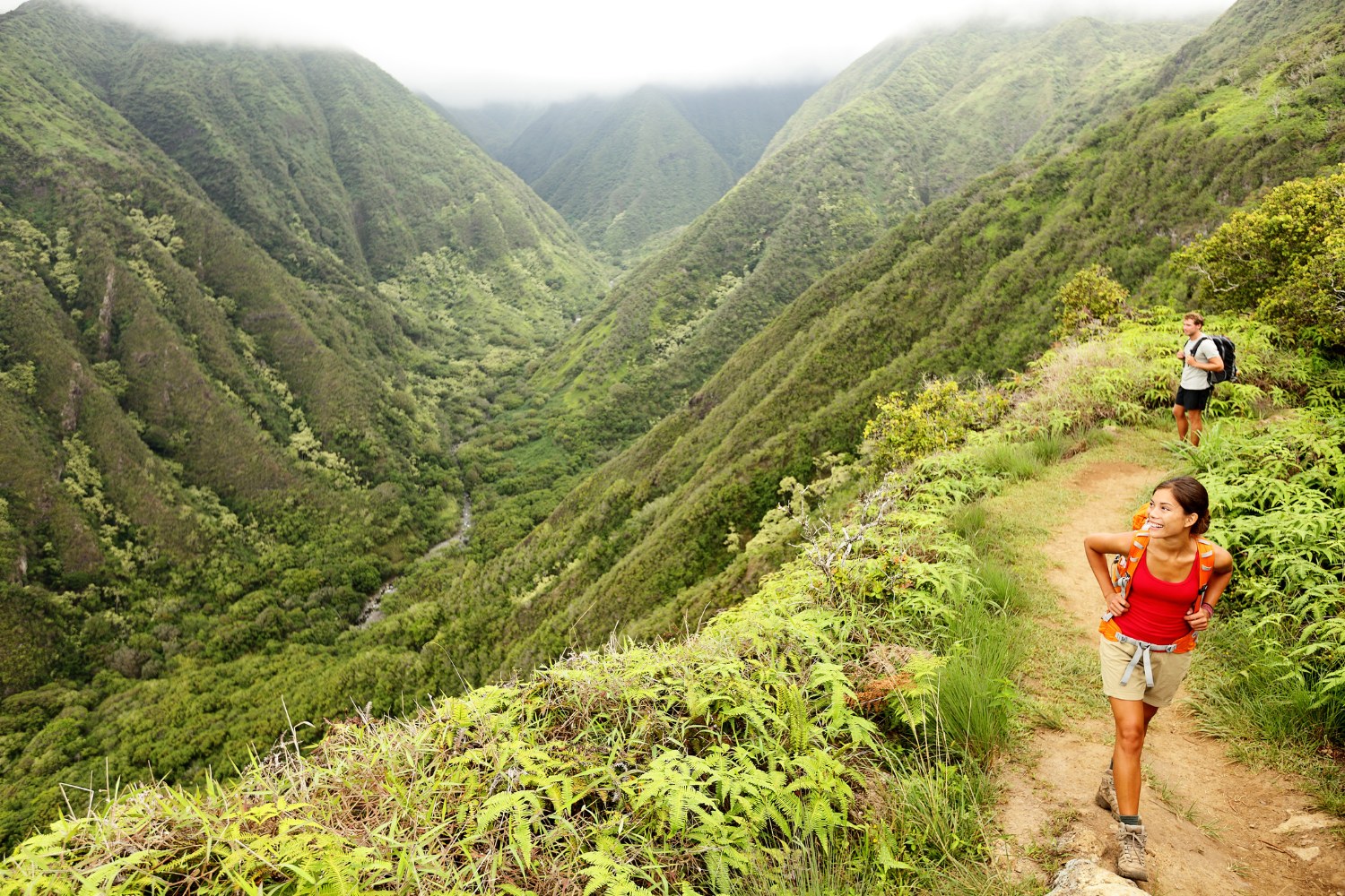 a man and woman hiking along the steep and rugged terrain near pu uka oku falls