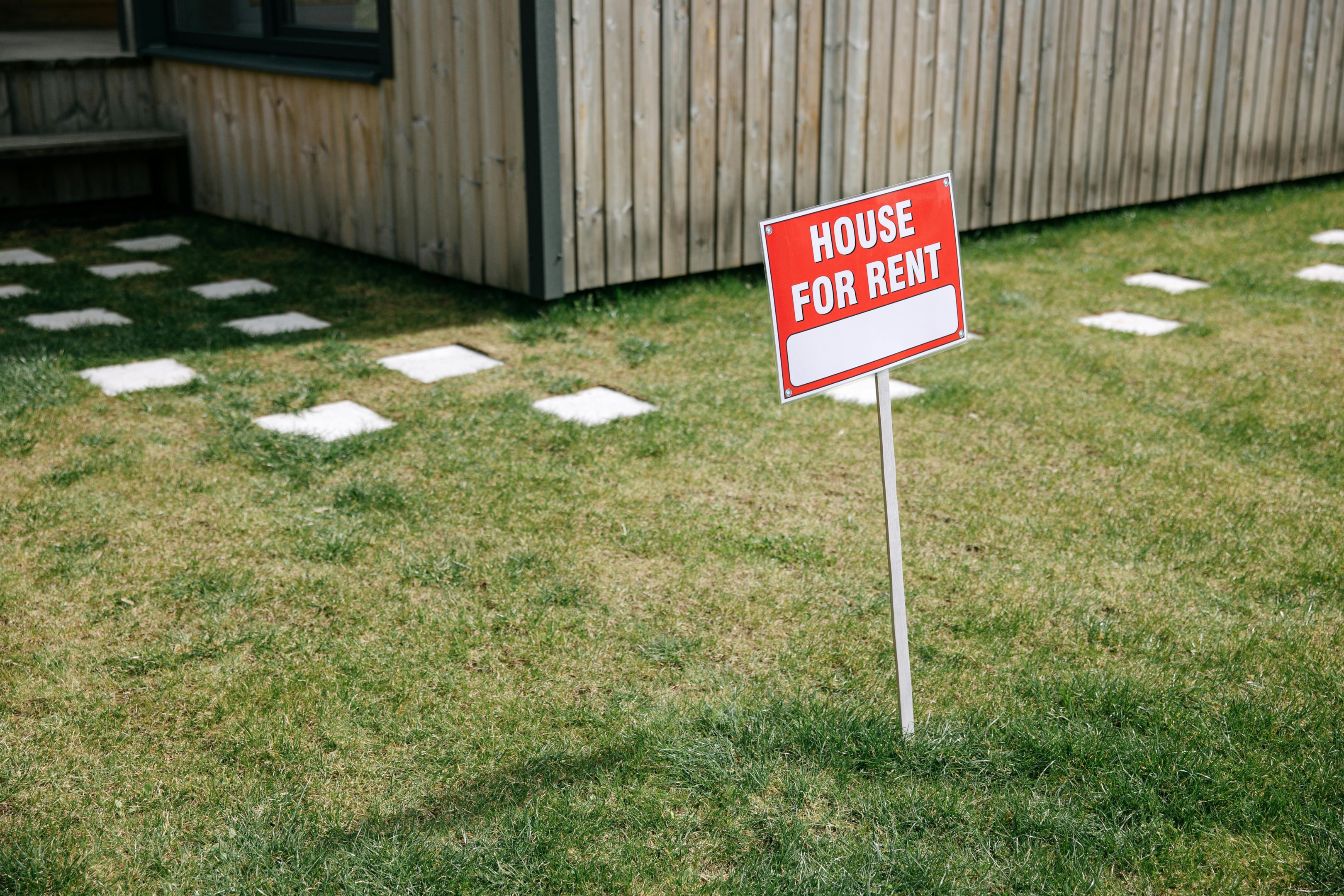 For Rent sign in front of house managed by a property manager. 