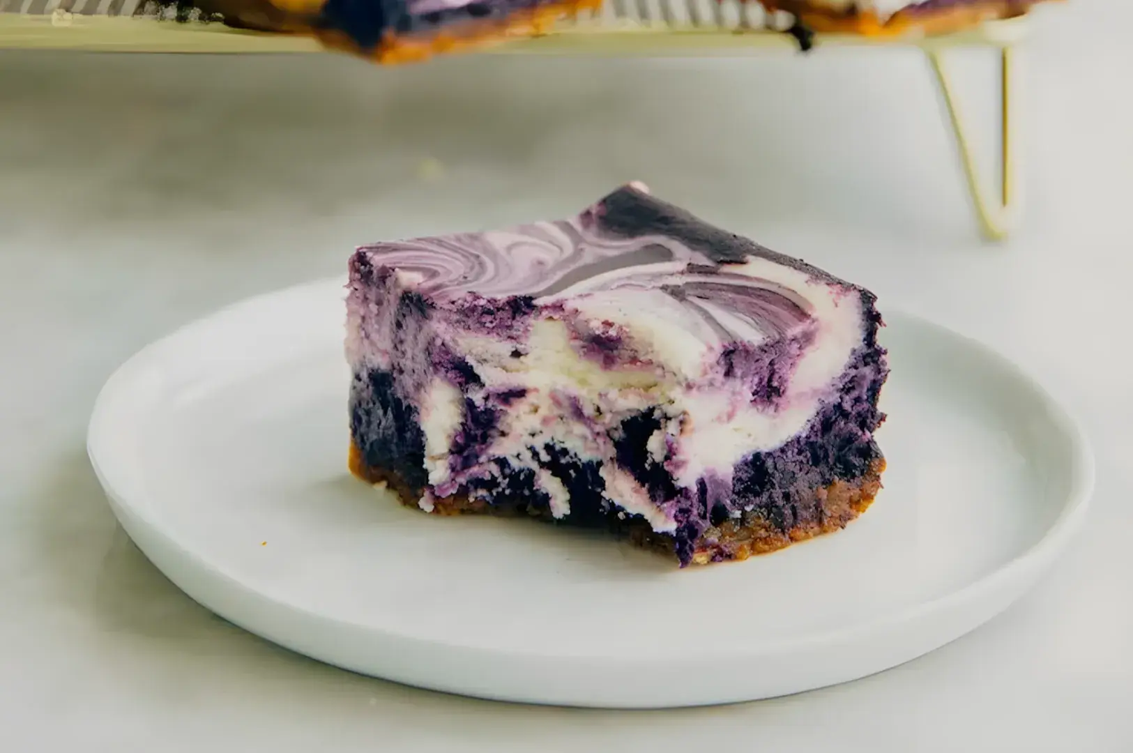 A slice of purple swirled dessert on a white plate, with a crust visible underneath.