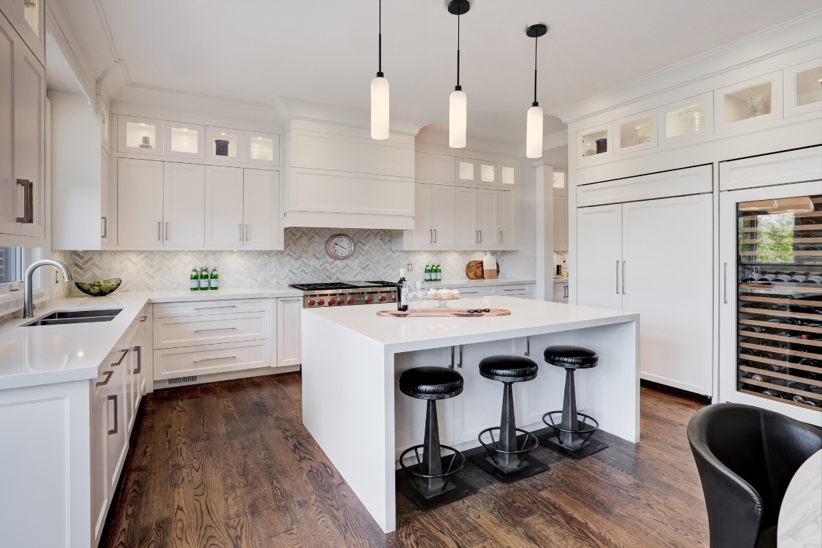 Pendant light trio over a white kitchen island, adding airiness, black accents, and modern style to a bright kitchen.