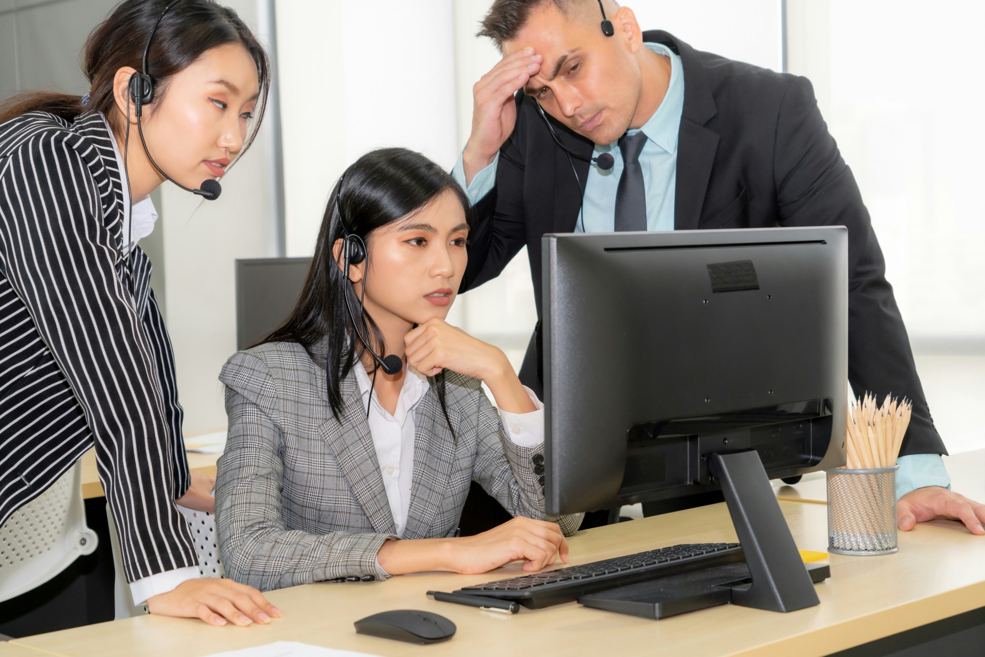 Three people sitting around a computer looking confused
