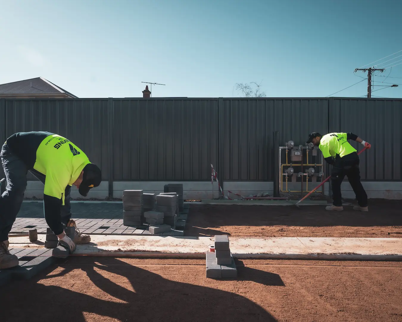 A large push broom being used to fill the joints between pavers