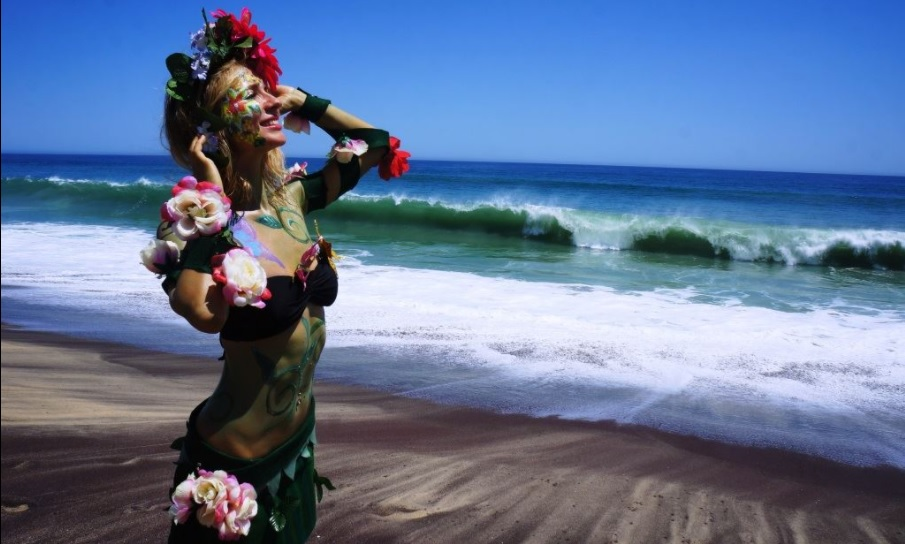 woman in a floral costume and body paint on the beach