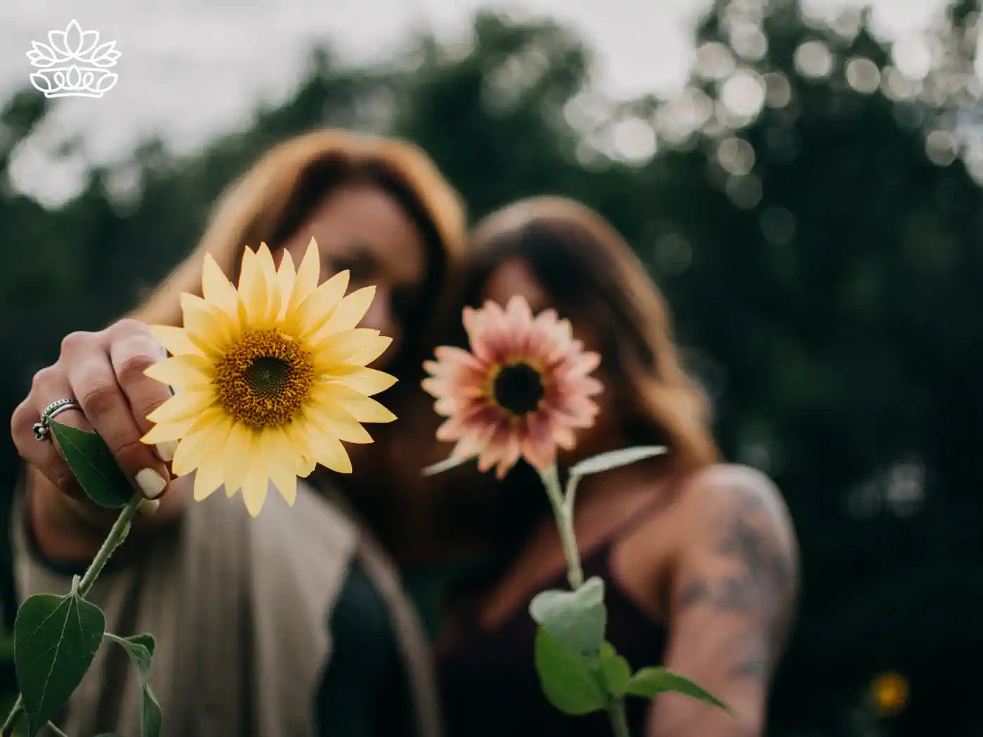 Two women holding sunflowers, with one woman in the background slightly out of focus. Fabulous Flowers and Gifts. Collection: Women's Day.