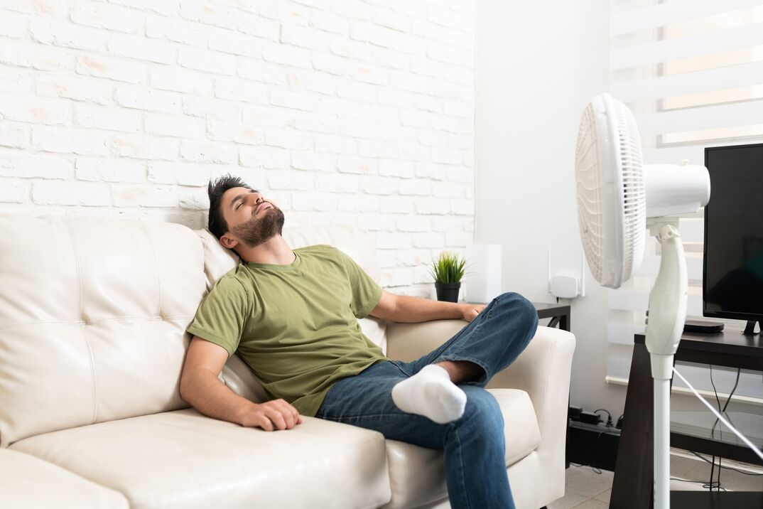 Man sitting in front of a fan at home 