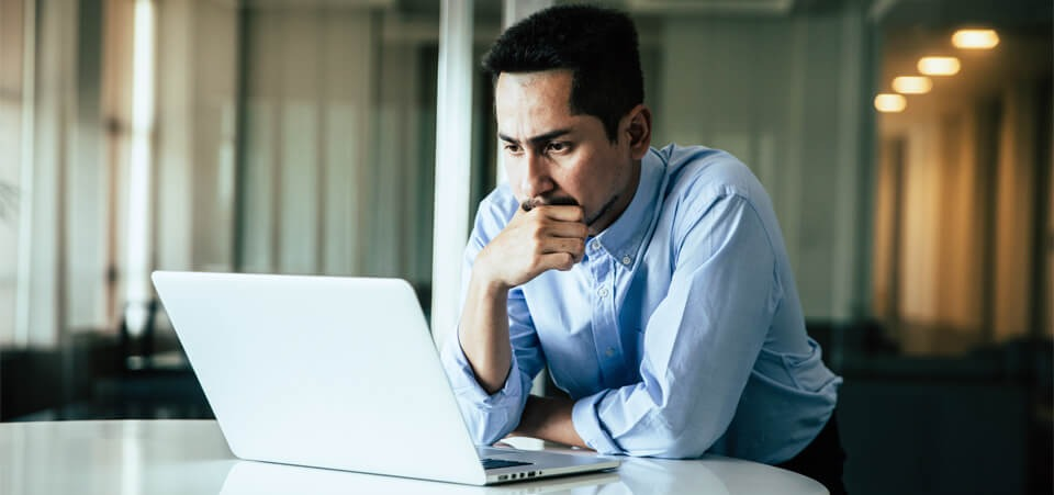 A man looking at a computer, concentrating hard
