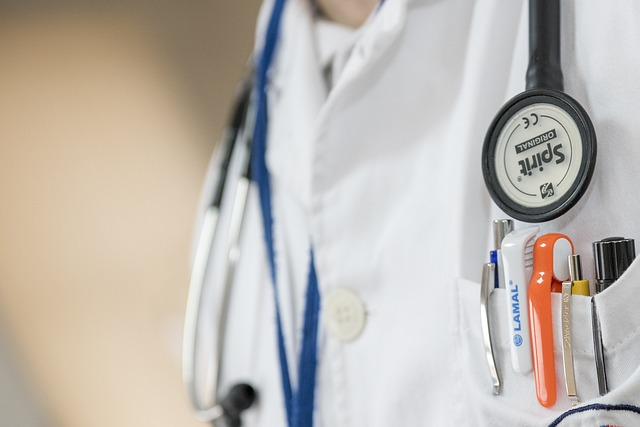 A cropped image of a doctor in a white lab coat with a stethoscope hanging from his neck. 