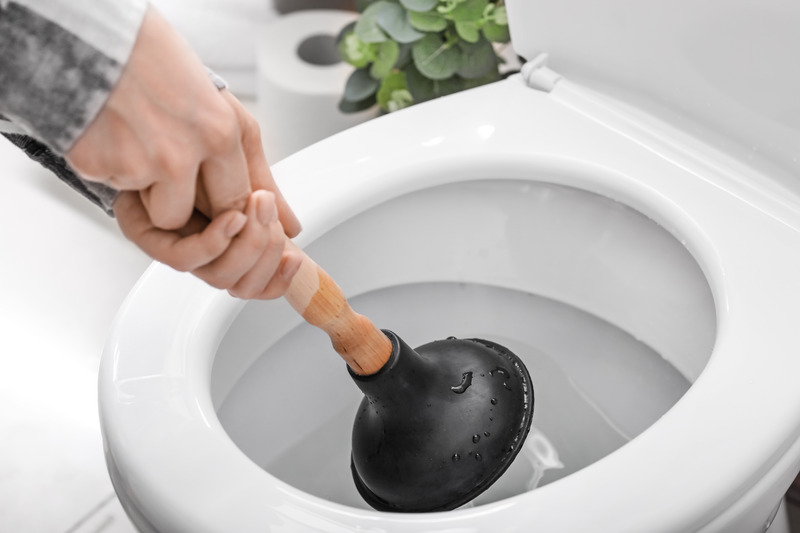 Person verwendet einen Pümpel, um eine verstopfte Toilette zu reparieren, ein häufiger Notfall für Installateur