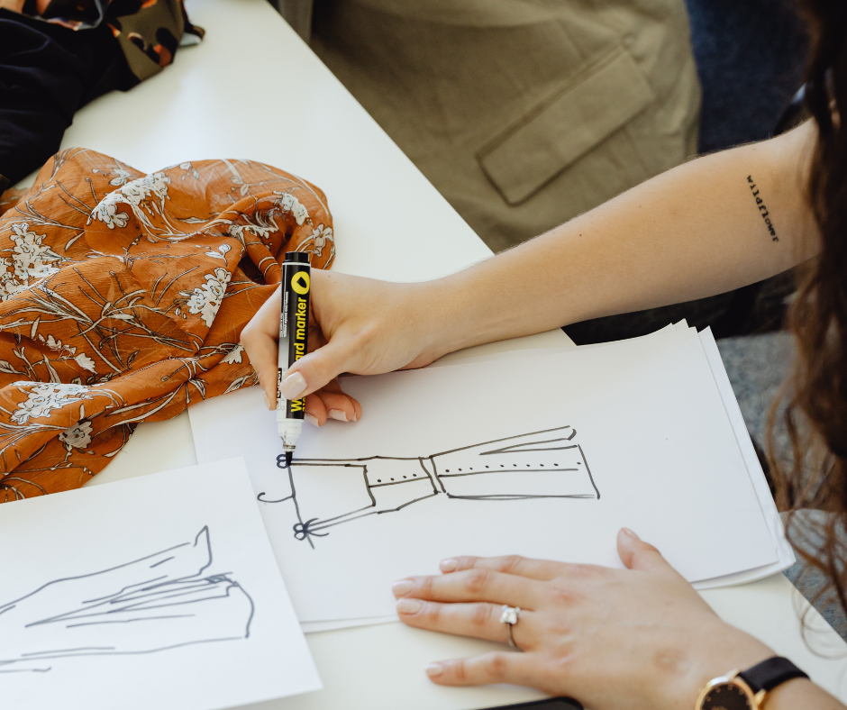 a woman uses a marker to sketch outfit ideas