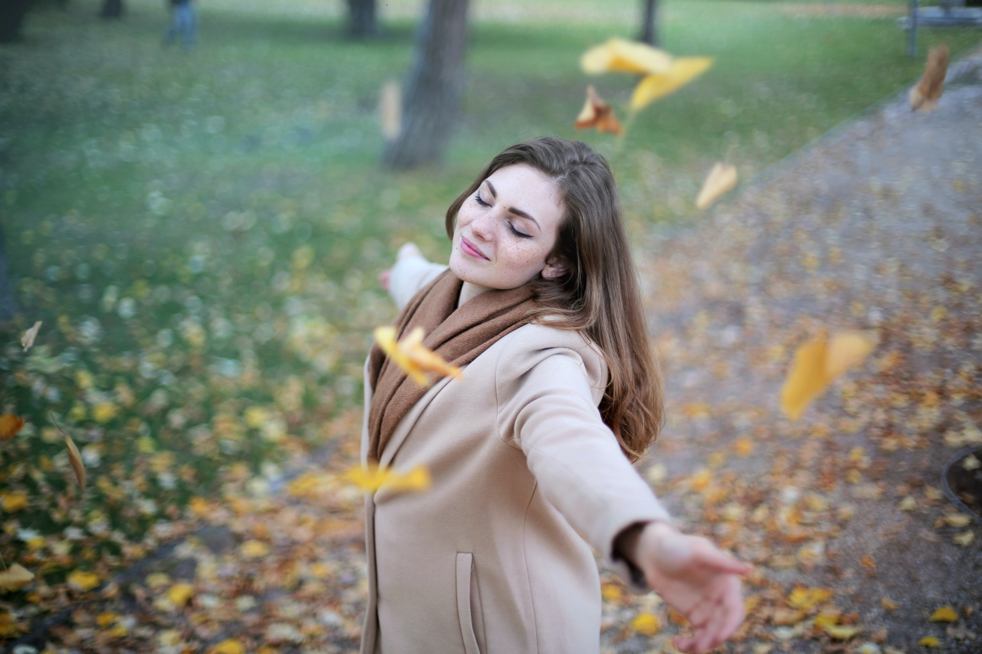 person dancing in the wind alone with falling leaves around them . rejoicing is learning how to be alone