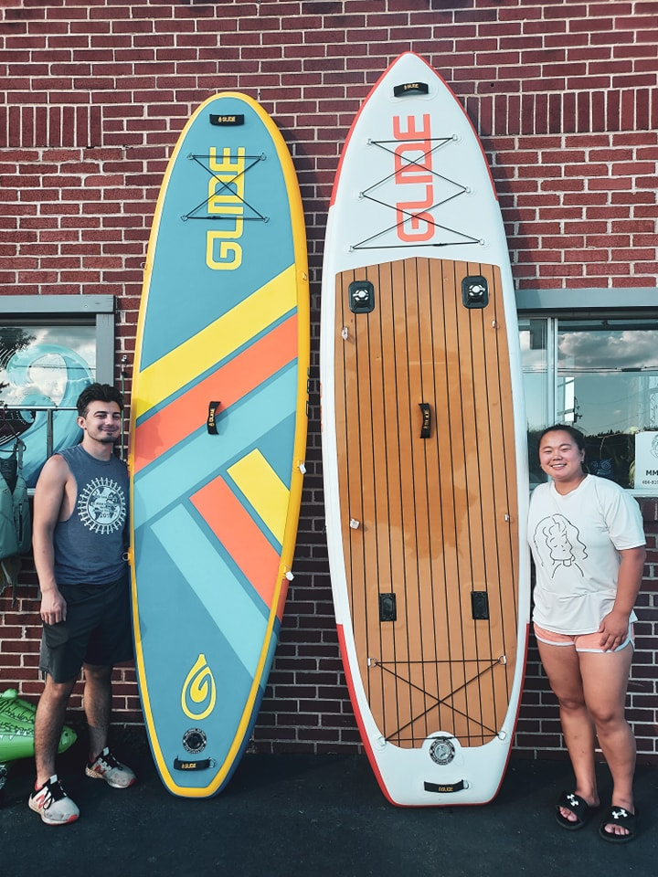 2 people holding inflatable paddle boards