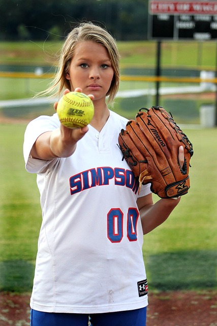 a girl wearing a softball glove holding a softball