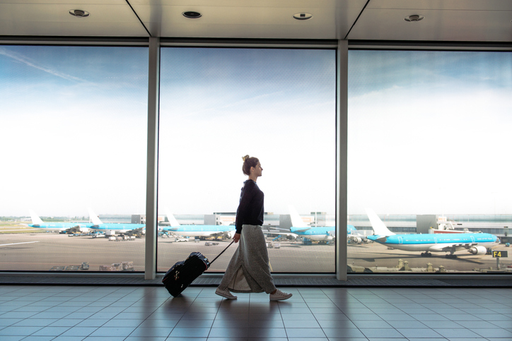 Young woman pulling her luggage through an airport.