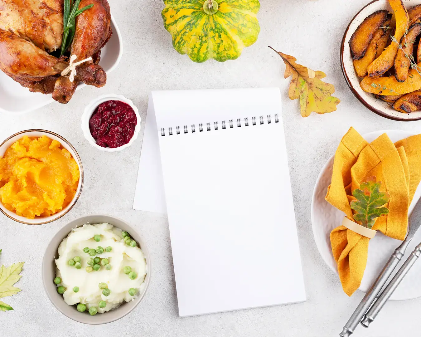 Restaurant meal planning workspace with notebook, roast chicken, mashed potatoes, vegetables, and seasonal side dishes