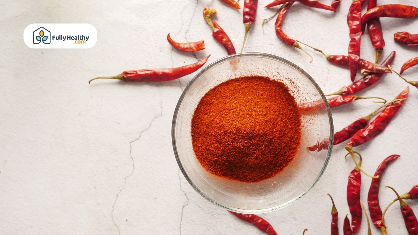 Glass bowl of chili powder surrounded by dried whole red chilies