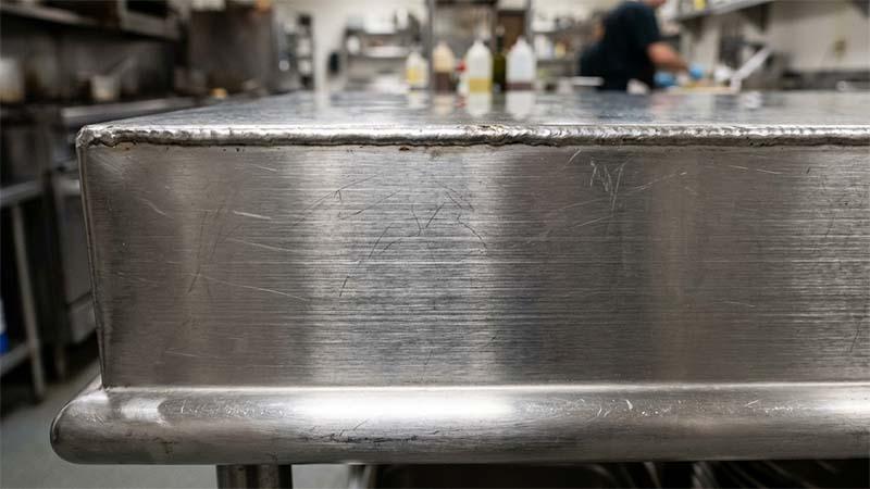Edge of a Stainless steel table showing grain direction
