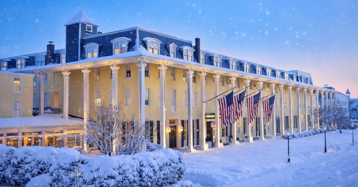 Congress Hall in Cape May during winter, decorated with American flags and surrounded by fresh snow at dusk