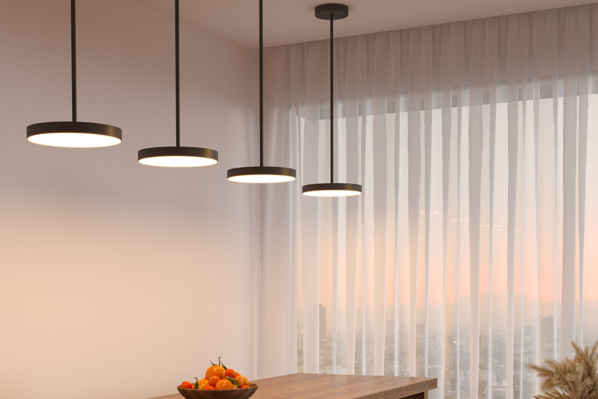 Black pendant light fixtures hanging over a dining room table, adding warm illumination, airiness, and modern style to the room.