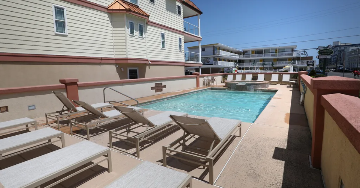 Outdoor pool at Carousel By the Sea in Wildwood Crest with lounge chairs and a relaxing sun deck for guests.
